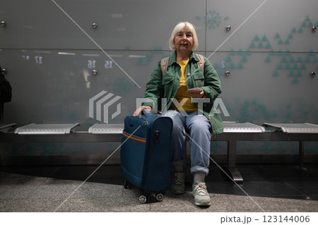 A passport, plane ticket and documents lie on a hand-held suitcase at the airport. A woman sits in the back seat waiting for her flight 123144006