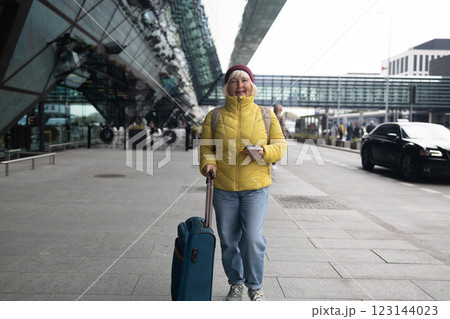 Young female traveler walking with a blue suitcase at the modern transport stop outdoors. Concept of an urban transportation and travel 123144023