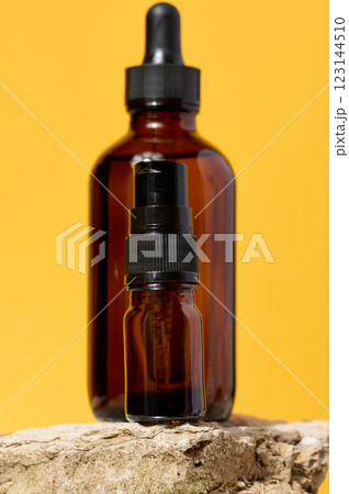A glass brown bottle with a dropper on a yellow background, a container for cosmetic products 123144510