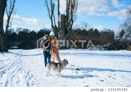 Couple enjoys winter walk with husky dog in snowy park 123145191