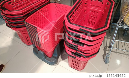 A collection of stacked red shopping baskets neatly organized in a retail store setting 123145432