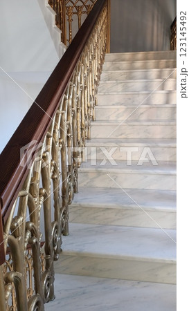 An Elegant Marble Staircase showcases an Ornate Railing with beautiful detailing and craftsmanship An Elegant Marble Staircase showcases an Ornate Railing with beautiful detailing and craftsmanship 123145492