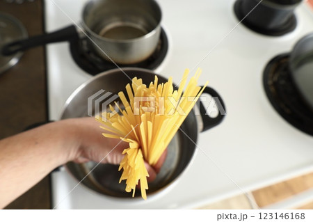 A hand lowers pasta into a saucepan 123146168