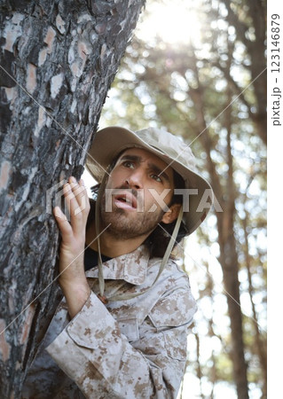 Scared Soldier Hides Behind The Trunk Of A Tree In The Mountains From The Enemy Scared Soldier Hides Behind The Trunk Of A Tree In The Mountains From The Enemy 123146879