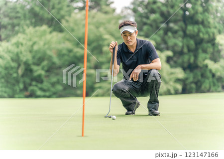 ゴルフ場のグリーン上でラインを読む男性ゴルファー 123147166