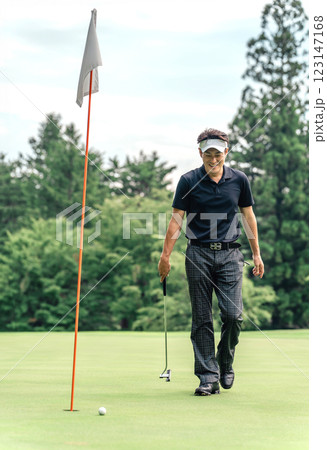 ゴルフ場のグリーン上を歩く笑顔の男性ゴルファー ゴルフ場のグリーン上を歩く笑顔の男性ゴルファー 123147168