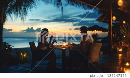 Romantic couple enjoys a candlelit dinner on a beach at sunset. 123147323