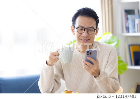 スマホを見ながら食事をする男性 123147483