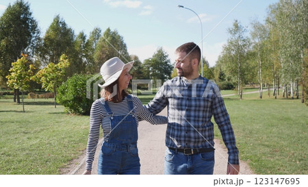 A happy couple walks along a pedestrian path in a city summer park 123147695