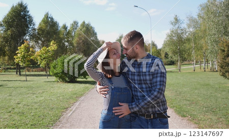 A loving couple shares a very tender and affectionate moment in a lush park under bright blue skies above 123147697