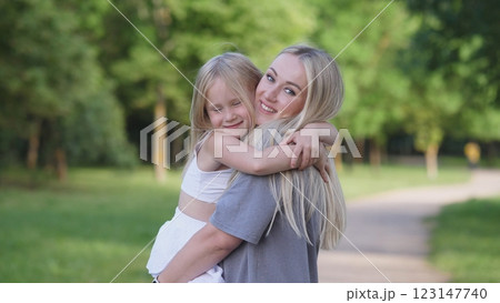 A heartwarming scene of a loving mother embracing her joyful daughter outdoors, showcasing love and happiness A heartwarming scene of a loving mother embracing her joyful daughter outdoors, showcasing love and happiness 123147740