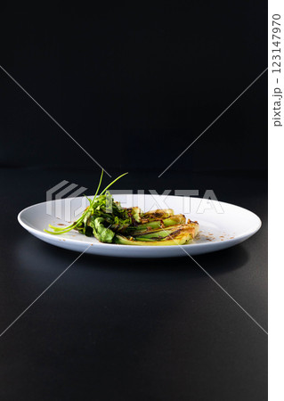 Bok choy is elegantly arranged on a white plate, showcasing vibrant greens against a dark setting. 123147970