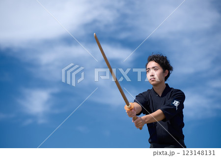 青空のもと木刀を構える若い男性 123148131