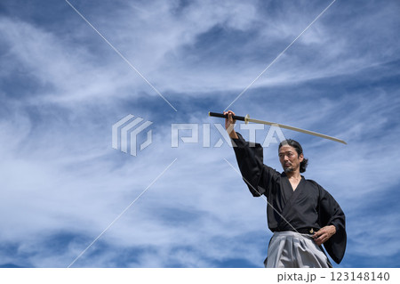 青空のもと刀を構える和服の男 123148140