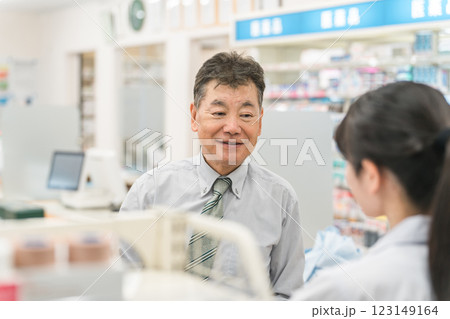 薬局で薬剤師から服薬指導を受けるシニア男性 123149164