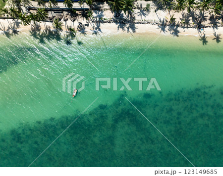 Emerald green water with visible seabed and a small fishing boat near the shore, lined with palm tree shadows. Koh Samui, Thailand. Emerald green water with visible seabed and a small fishing boat near the shore, lined with palm tree shadows. Koh Samui, Thailand. 123149685