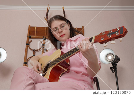 Young woman playing guitar performs in strumming style of acoustic classical guitar 123150070