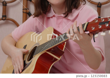 Close-up woman guitarist is practicing skills of playing on six string acoustic guitar 123150083