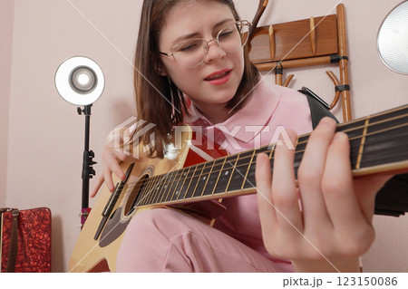 Young woman playing classical six string acoustic guitar and singing song and shaking head to beat Young woman playing classical six string acoustic guitar and singing song and shaking head to beat 123150086