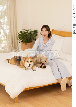 Side view of woman sitting on bed with dog 123152795