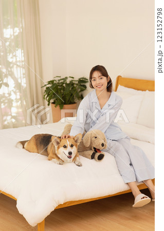 Side view of woman sitting on bed with dog Side view of woman sitting on bed with dog 123152798