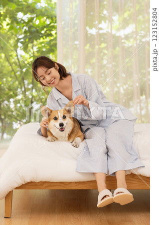 Side view of woman sitting on bed with dog 123152804