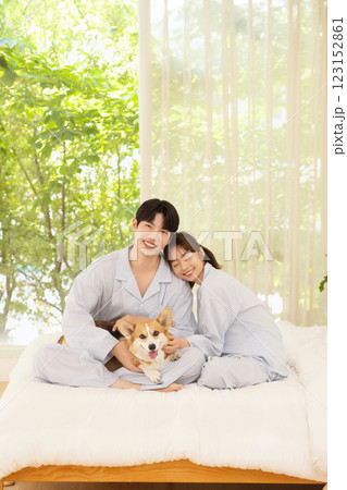 Cropped view of young couple sitting on bed with dog Cropped view of young couple sitting on bed with dog 123152861