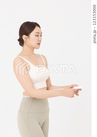 Cropped view of young woman measuring waist circumference wearing sportswear 123153000