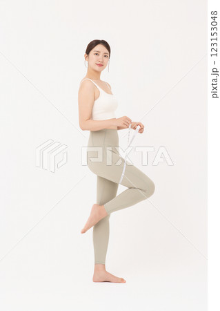 Cropped view of young woman wearing sportswear measuring leg circumference 123153048