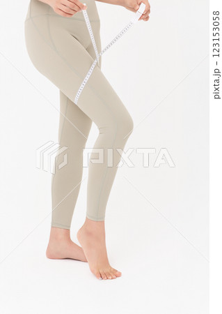Cropped view of young woman wearing sportswear measuring leg circumference 123153058