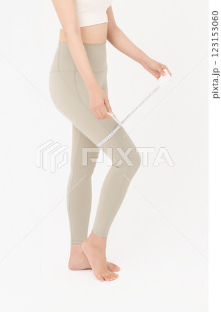 Cropped view of young woman wearing sportswear measuring leg circumference Cropped view of young woman wearing sportswear measuring leg circumference 123153060