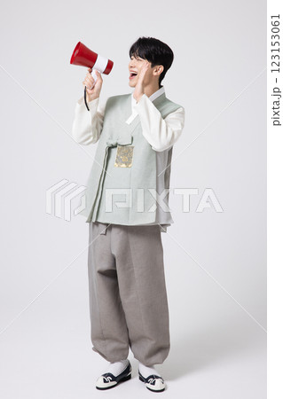 A young man wearing a hanbok and shouting while holding a megaphone A young man wearing a hanbok and shouting while holding a megaphone 123153061