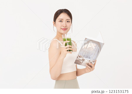 Portrait of young woman wearing sportswear, drinking healthy drink and reading book 123153175