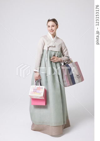 A Western woman standing wearing a Hanbok and holding shopping bags 123153176