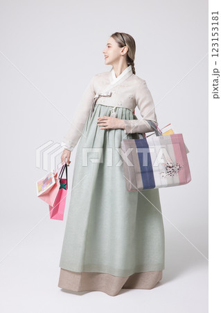 A Western woman standing wearing a Hanbok and holding shopping bags 123153181