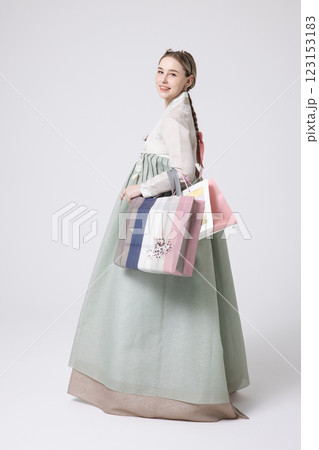 A Western woman standing wearing a Hanbok and holding shopping bags A Western woman standing wearing a Hanbok and holding shopping bags 123153183