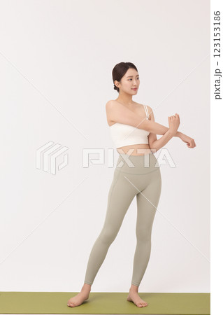 Portrait of a young woman wearing sportswear and stretching on a yoga mat Portrait of a young woman wearing sportswear and stretching on a yoga mat 123153186
