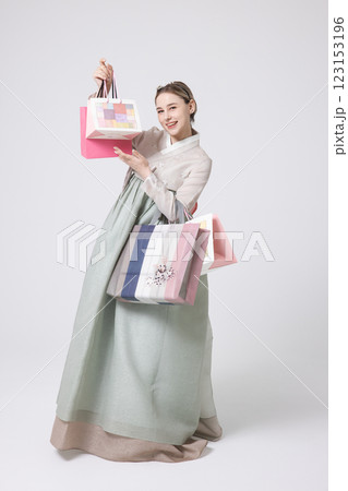 A Western woman standing wearing a Hanbok and holding shopping bags 123153196