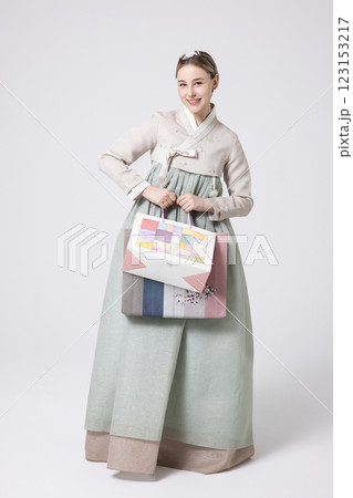 A Western woman standing wearing a Hanbok and holding shopping bags A Western woman standing wearing a Hanbok and holding shopping bags 123153217