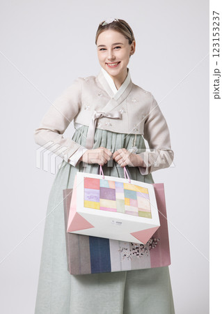 A Western woman standing wearing a Hanbok and holding shopping bags 123153237