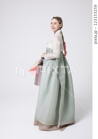 A Western woman standing wearing a Hanbok and holding shopping bags 123153259