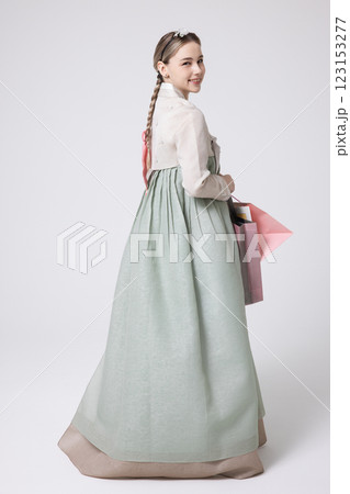 A Western woman standing wearing a Hanbok and holding shopping bags 123153277