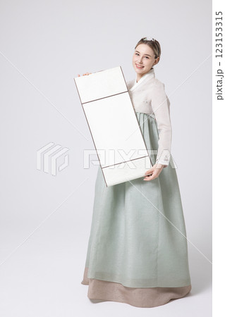 A Western woman standing wearing a Hanbok and holding a hanging scroll 123153315