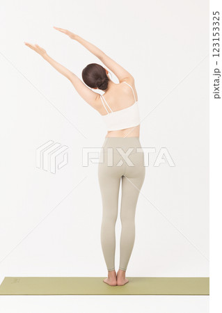 Portrait of a young woman wearing sportswear and stretching on a yoga mat 123153325