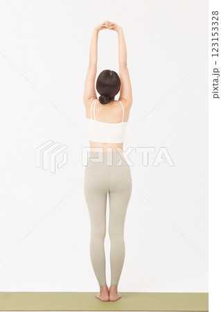 Portrait of a young woman wearing sportswear and stretching on a yoga mat 123153328