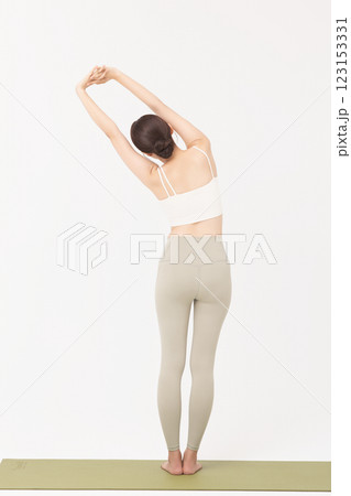 Portrait of a young woman wearing sportswear and stretching on a yoga mat 123153331