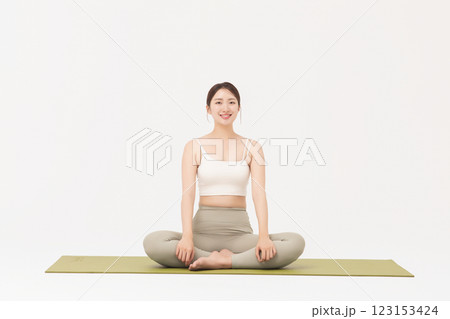 Portrait of a young woman wearing sportswear sitting on a yoga mat and stretching 123153424