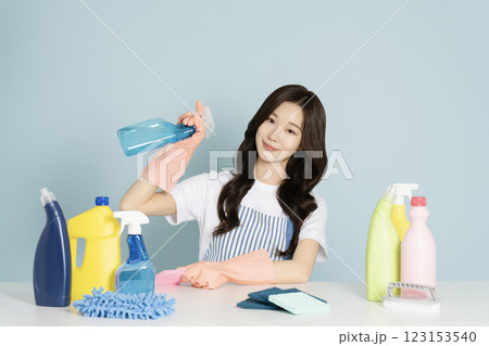 A 23-year-old woman sitting in front of a table, wearing rubber gloves and holding a cleaning tool 123153540
