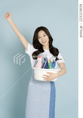 A woman in her 20s holding a basin containing cleaning tools for cleaning 123153639