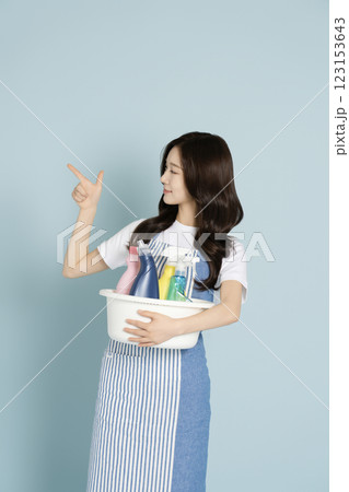 A woman in her 20s holding a basin containing cleaning tools for cleaning 123153643